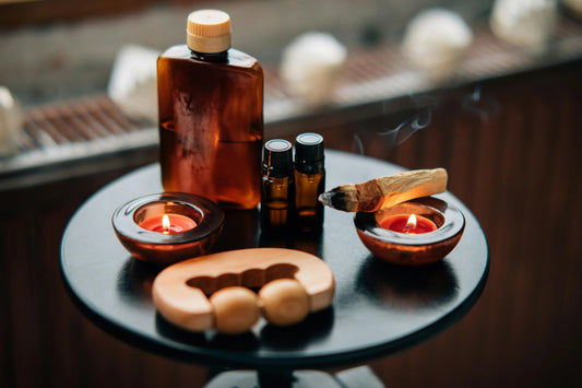 Palo Santo candles, oils, and smudge stick on a wellness table display.