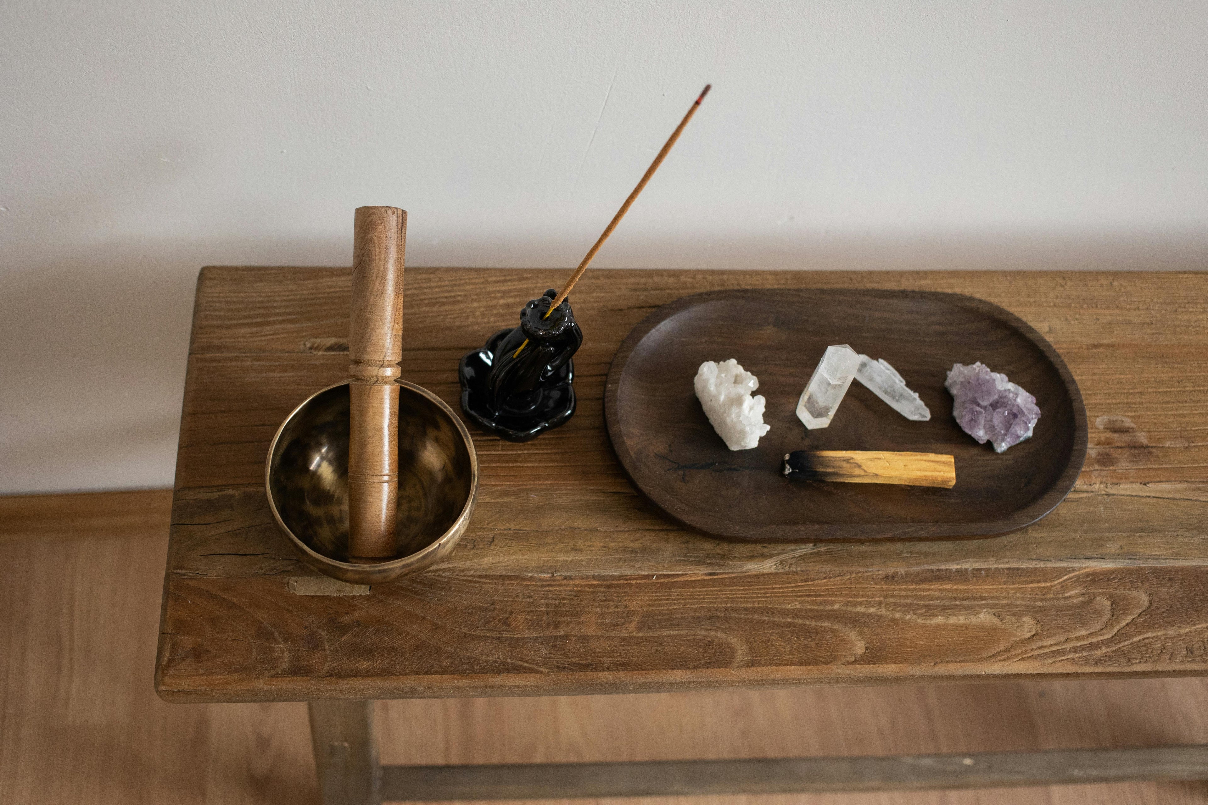 Palo Santo and healing crystals on wooden table with incense and singing bowl