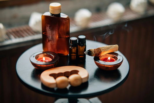 Palo Santo candles, oils, and smudge stick on a wellness table display.